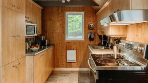 Una cucina compatta con mobili in legno, un forno a microonde, un fornello e una finestra con vista sull'esterno.