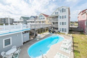 A swimming pool with lounge chairs and a deck area, surrounded by multi-story buildings with balconies.