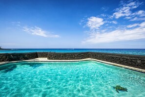 A clear blue pool with a stone wall and a view of the ocean. - KONA MAGIC SANDS#213 2ND FLOOR DIRECT BEACHFRONT, BEST VIEWS IN KONA! (Kailua Kona)