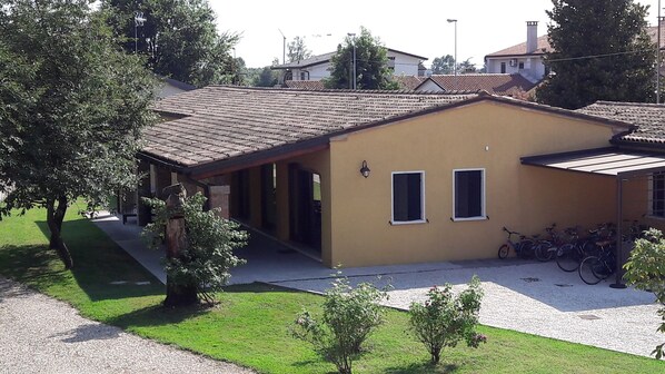 A two-story house with a tiled roof, a covered porch, and a small garden area with a gravel path.