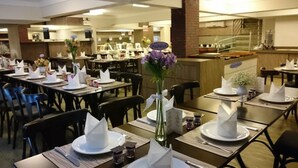 Un restaurant où les tables sont dressées pour le service, avec des serviettes blanches et un vase orné de fleurs violettes.