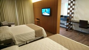 Une chambre d’hôtel avec deux lits, un téléviseur fixé au mur, un bureau et une chaise.