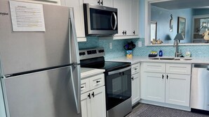 A modern kitchen with white cabinets, a stainless steel refrigerator, a microwave, an oven, and a dishwasher. - Oceanview, steps from Beach, Pool, Golf course & Restaurant, newly remodeled.  (Saint Helena Island)
