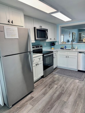 A modern kitchen with white cabinets, a stainless steel refrigerator, a microwave, an oven, and a dishwasher. - Oceanview, steps from Beach, Pool, Golf course & Restaurant, super clean! (Saint Helena Island)