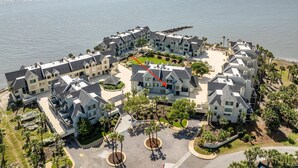 A coastal residential area with multiple two-story houses, a central courtyard, and a view of the ocean. - Oceanview, steps from Beach, Pool, Golf course & Restaurant, newly remodeled.  (Saint Helena Island)