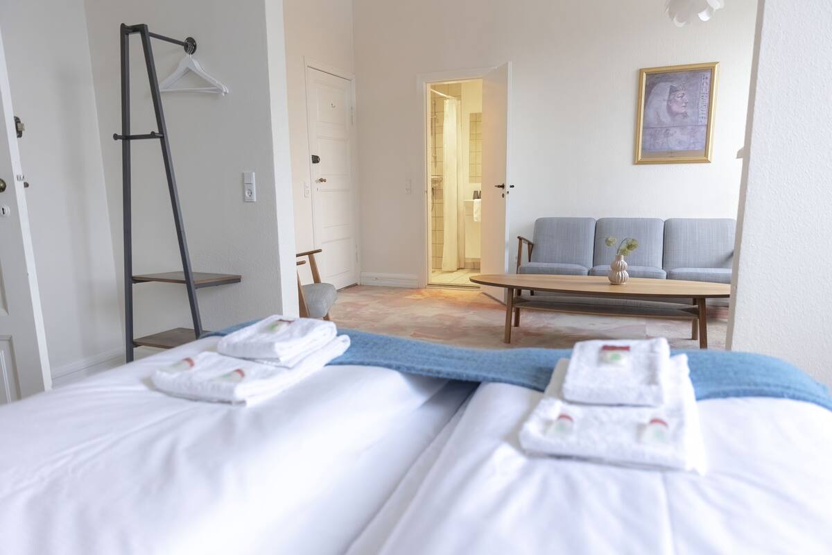 Habitación de hotel con cama, escritorio, silla y zona de ducha.