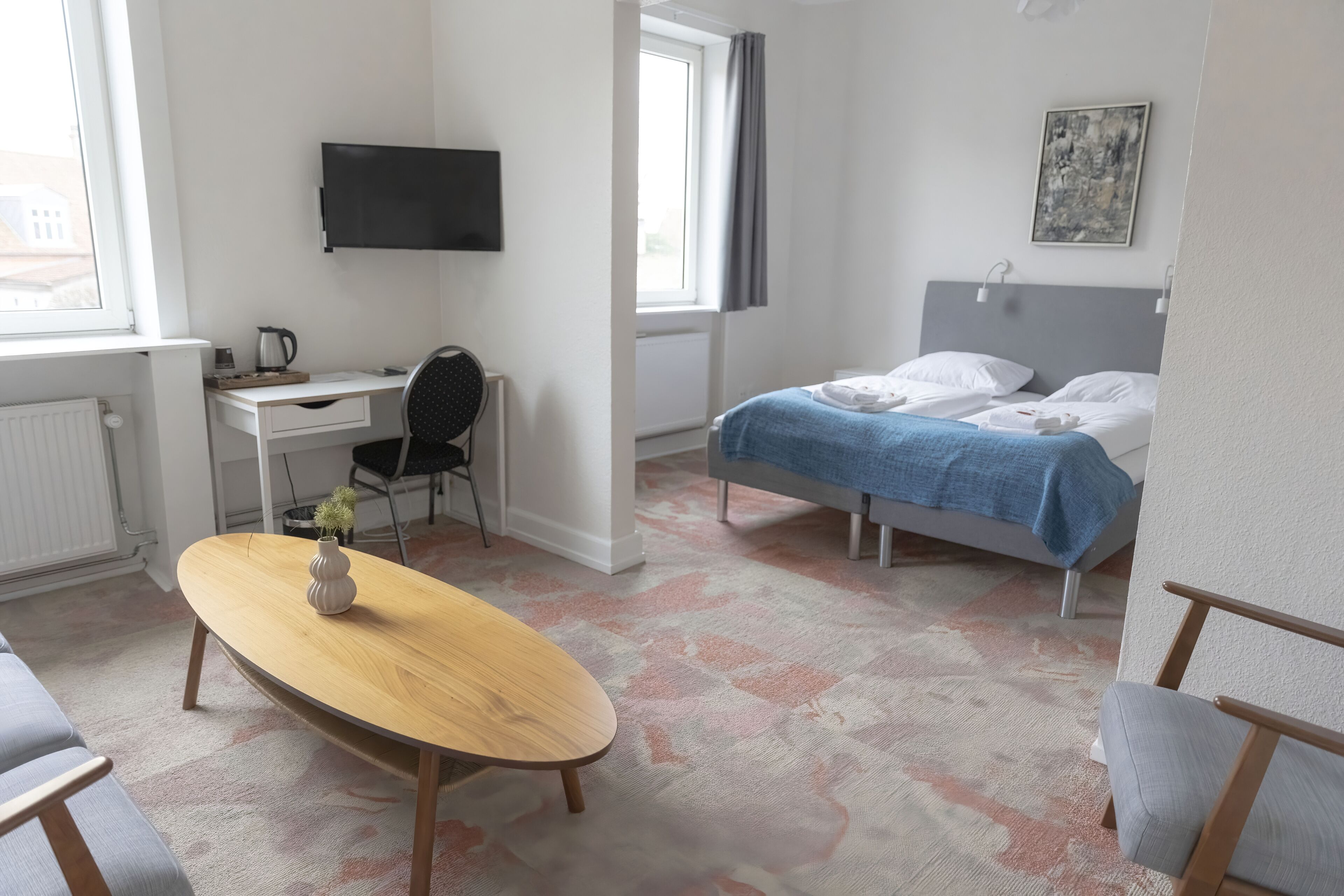 Un dormitorio con cama, escritorio, silla, televisión y ventana.