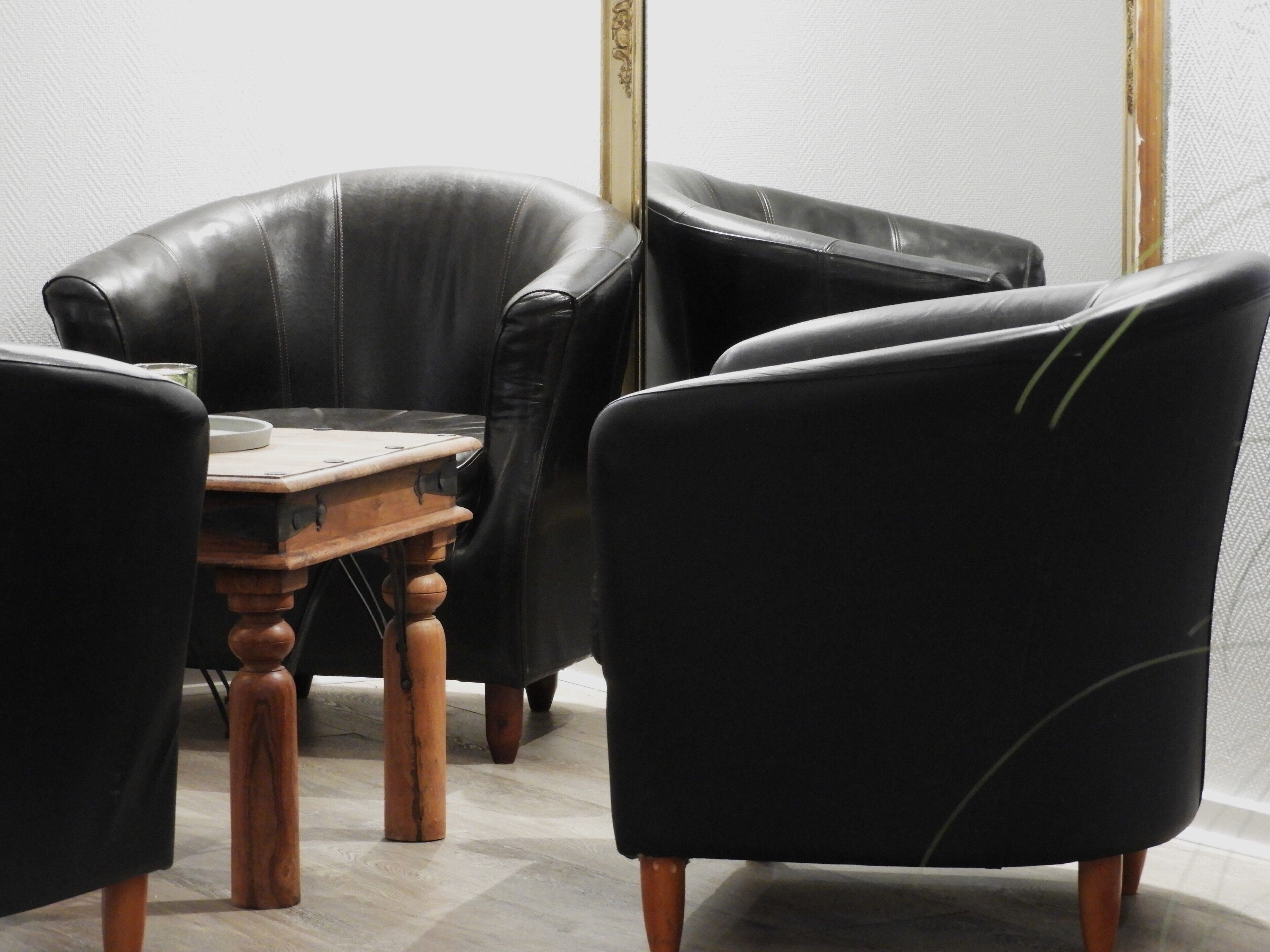 A room with a wooden table and four black leather chairs.