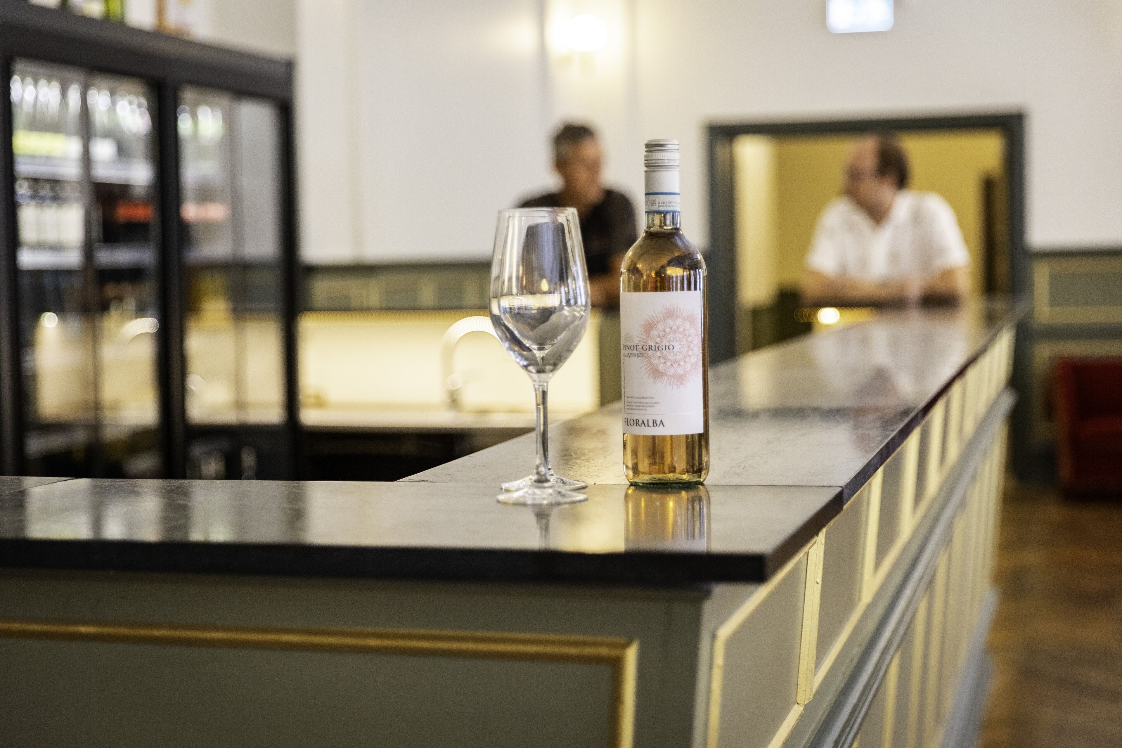 A bar area with a bottle of wine and a glass on the counter.