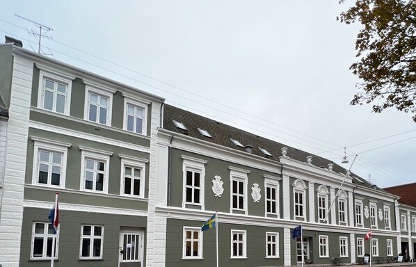 Un immeuble à plusieurs étages, avec des éléments décoratifs blancs et de nombreuses fenêtres.