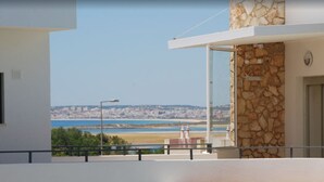 En balkon med frit udsyn over en kystby, inklusive en strand og fjerne bygninger.