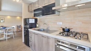 A modern kitchen with a stainless steel refrigerator, a gas stove, and wooden cabinets.