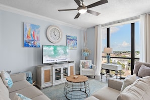 A living room with a television, a clock, and artwork on the wall.