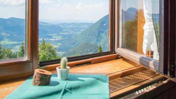 Una habitación con un ventanal que ofrece vistas a un valle y montañas.