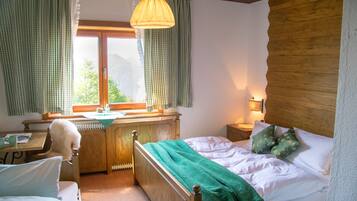A bedroom with a wooden bed, a desk, and a chair.