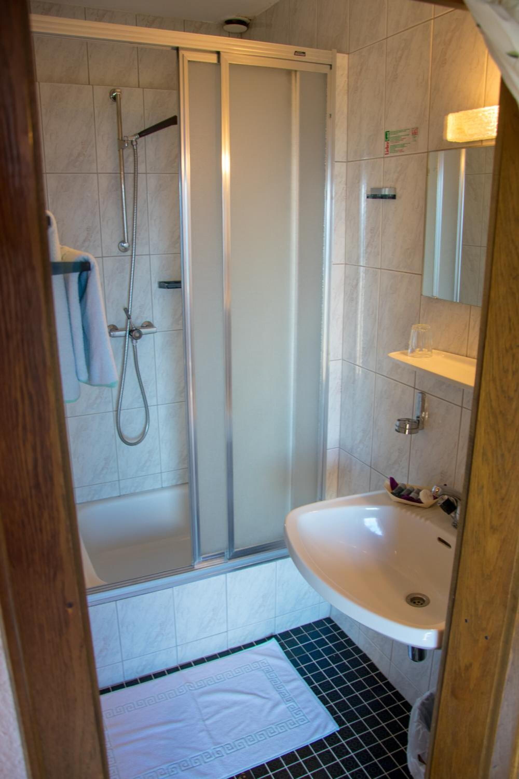 A bathroom with a shower, sink, and mirror.