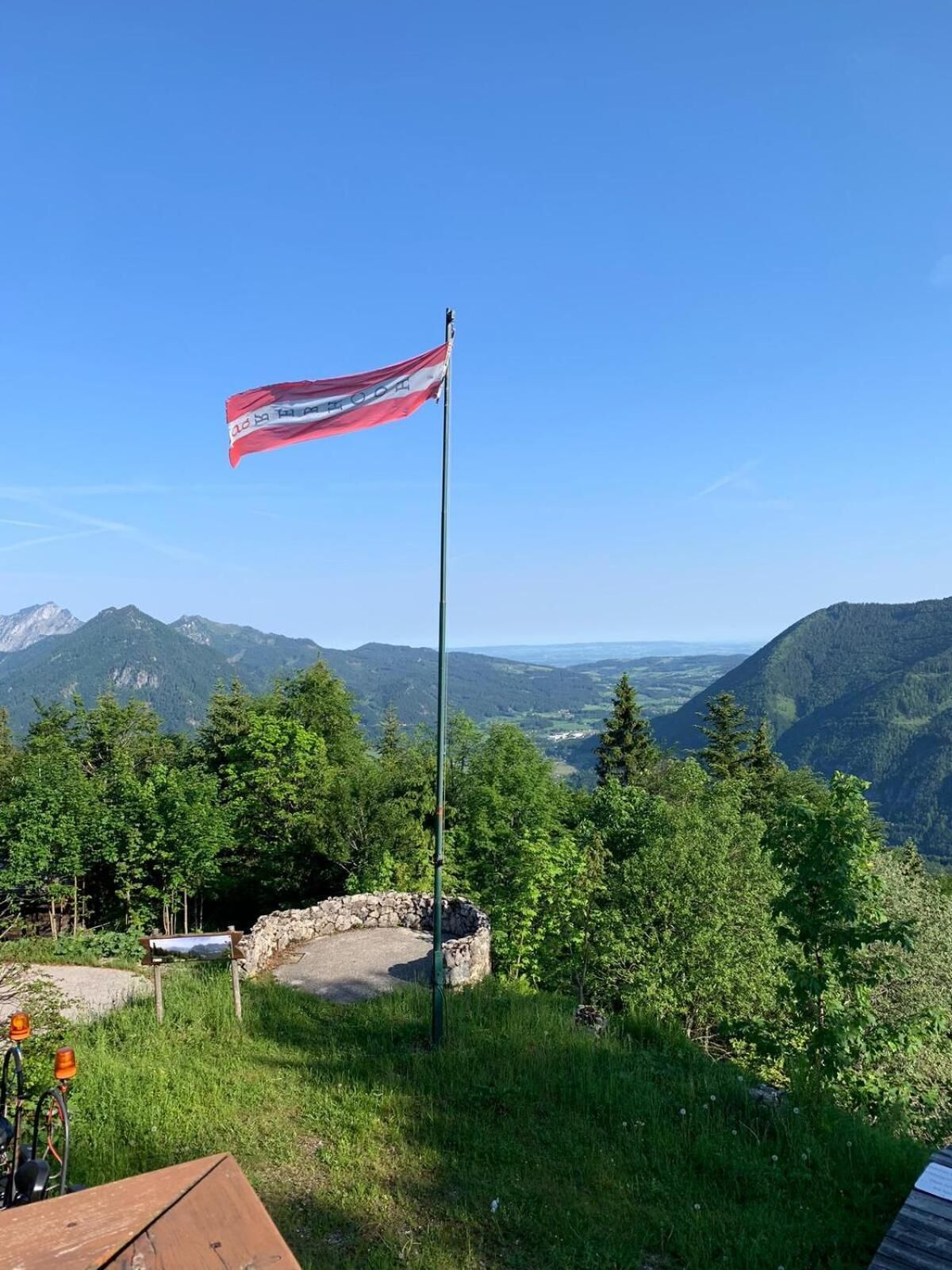 En flagga på en flaggstång med ett bergigt landskap i bakgrunden.