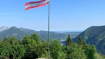 Een vlag op een vlaggenmast met een bergachtig landschap op de achtergrond.