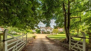 A gravel pathway leading to a house with a white facade, surrounded by greenery and a stone wall. - Beacon Lodge, Burnham Market, Norfolk (Burnham Market)