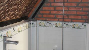 A bathroom with a white sink, a shower, and a tiled wall with floral patterns.
