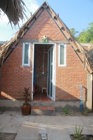 A small brick building with a sloped roof, a door, and a small porch area with a potted plant. - Bau Bi Mini Farmstay Mekong - Tien Giang (Trung An)