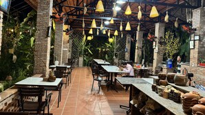 Un restaurante interior con paredes de ladrillo, lámparas amarillas colgantes y mesas con sillas.