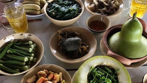 A table with various dishes and drinks, including bowls of food, a pitcher, and glasses of a yellow beverage. - Bau Bi Mini Farmstay Mekong - Tien Giang (Trung An)
