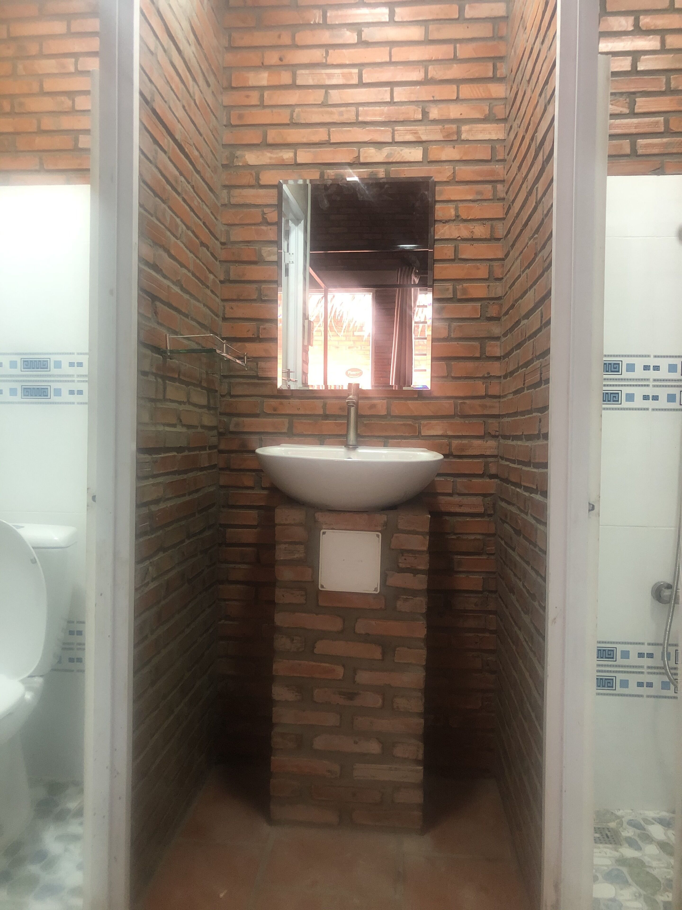 A bathroom with a white sink, a mirror, and a window.