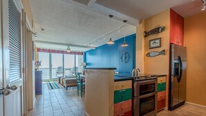 A kitchen with a central island, stainless steel appliances, and a view to a balcony.