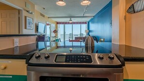 A kitchen with a stainless steel stove, a glass-top dining table, and a view of the city through large windows.