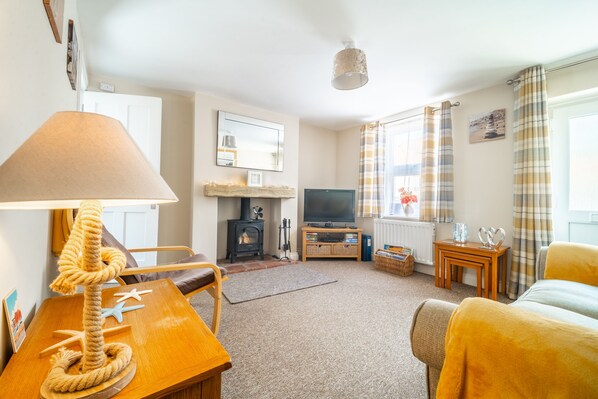 A cozy living room with a fireplace, a television, and a comfortable sofa.