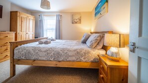 A bedroom with a wooden bed, a nightstand with a lamp, a wardrobe, and a painting on the wall. - Seaside Cottage, Wells-next-the-Sea, Norfolk (Wells-next-the-Sea)
