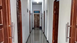 Um corredor longo e estreito com portas de madeira em ambos os lados e chão de azulejos.