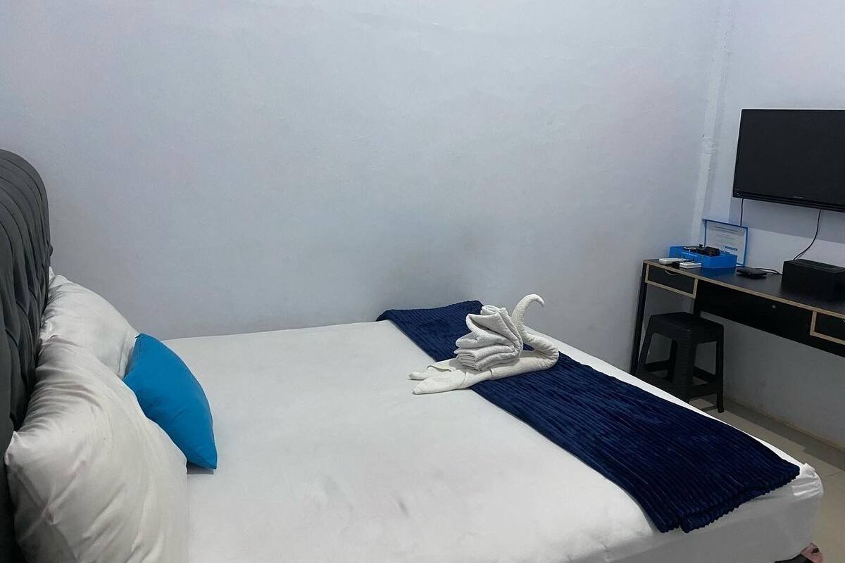 Een hotelkamer met een bed, bureau, stoel en televisie.