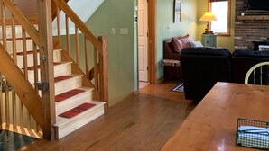 A multi-level wooden staircase with red carpeted steps leading to a loft area with a fireplace and a sofa.