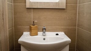 Un baño con un lavabo blanco, un dispensador de jabón de madera y un grifo.
