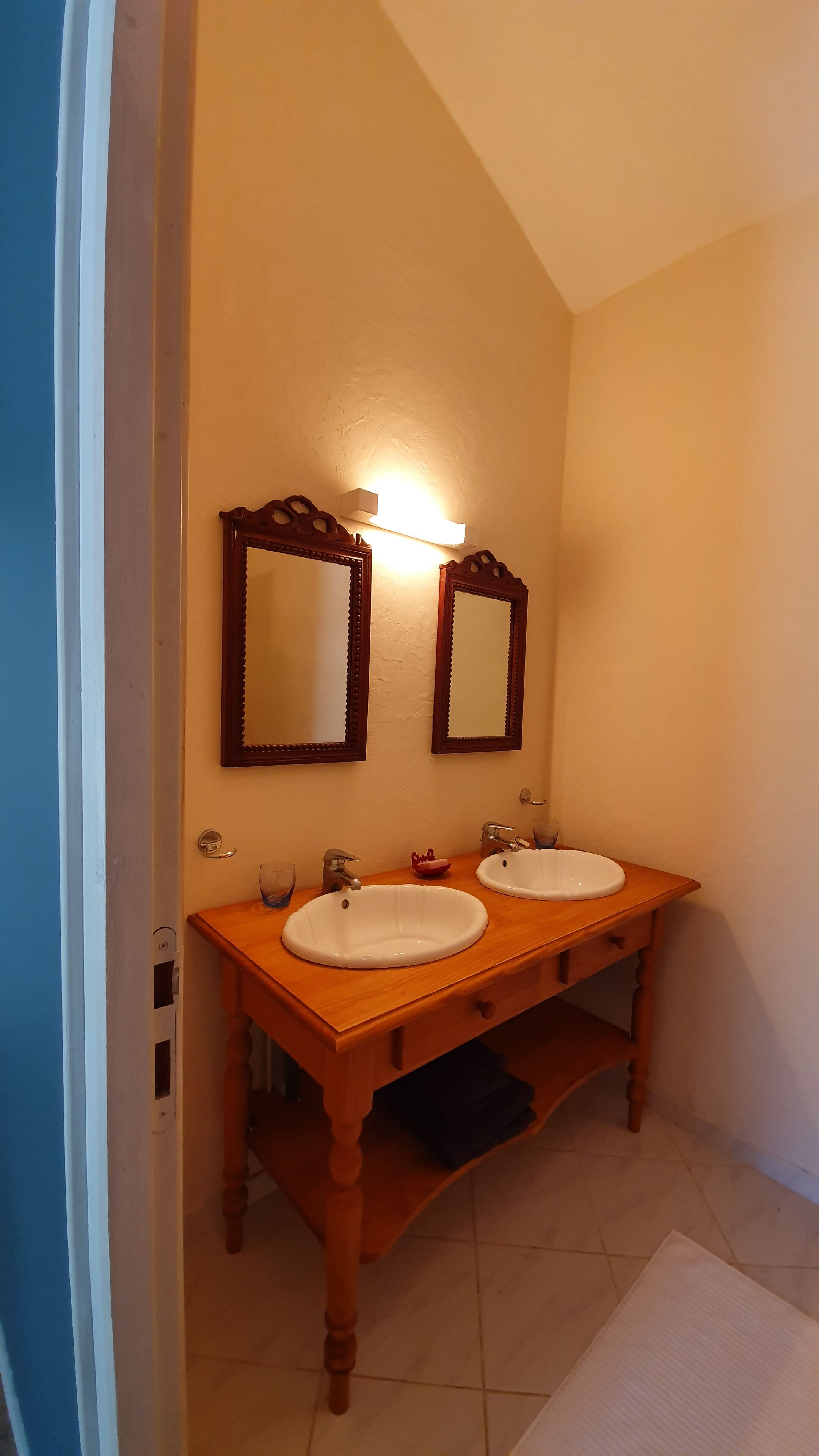 A bathroom with two sinks, wooden vanity, and two wall-mounted mirrors.