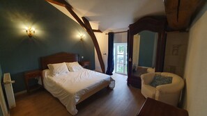 A bedroom with a wooden bed, a nightstand, a chair, and a window with a view of the outdoors. - La Prunelière, in the heart of nature (Razines)