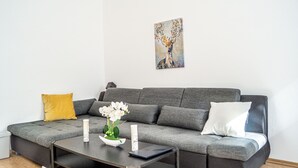 A modern living room with a grey sectional sofa, a small coffee table, and a white orchid centerpiece. - Shared Modern Apartment Schönbrunn - Budget Chic Room (Vienna)