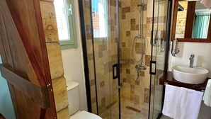 A bathroom with a glass-enclosed shower, a toilet, and a sink. - Monk Island Guesthouse (Foça)