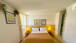 A hotel room with a bed, two bedside tables with lamps, a yellow striped rug, and framed pictures on the wall. - Monk Island Guesthouse (Foça)