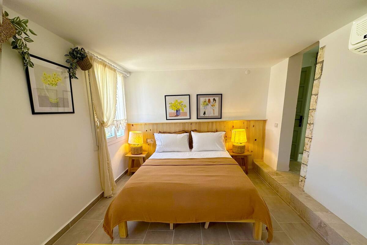 A hotel room with a bed, two bedside tables with lamps, a yellow striped rug, and framed pictures on the wall.