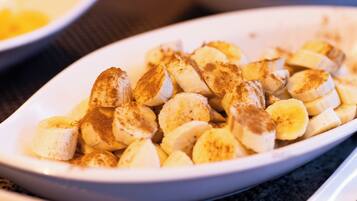 Une assiette ovale blanche remplie de rondelles de bananes saupoudrées de cannelle.