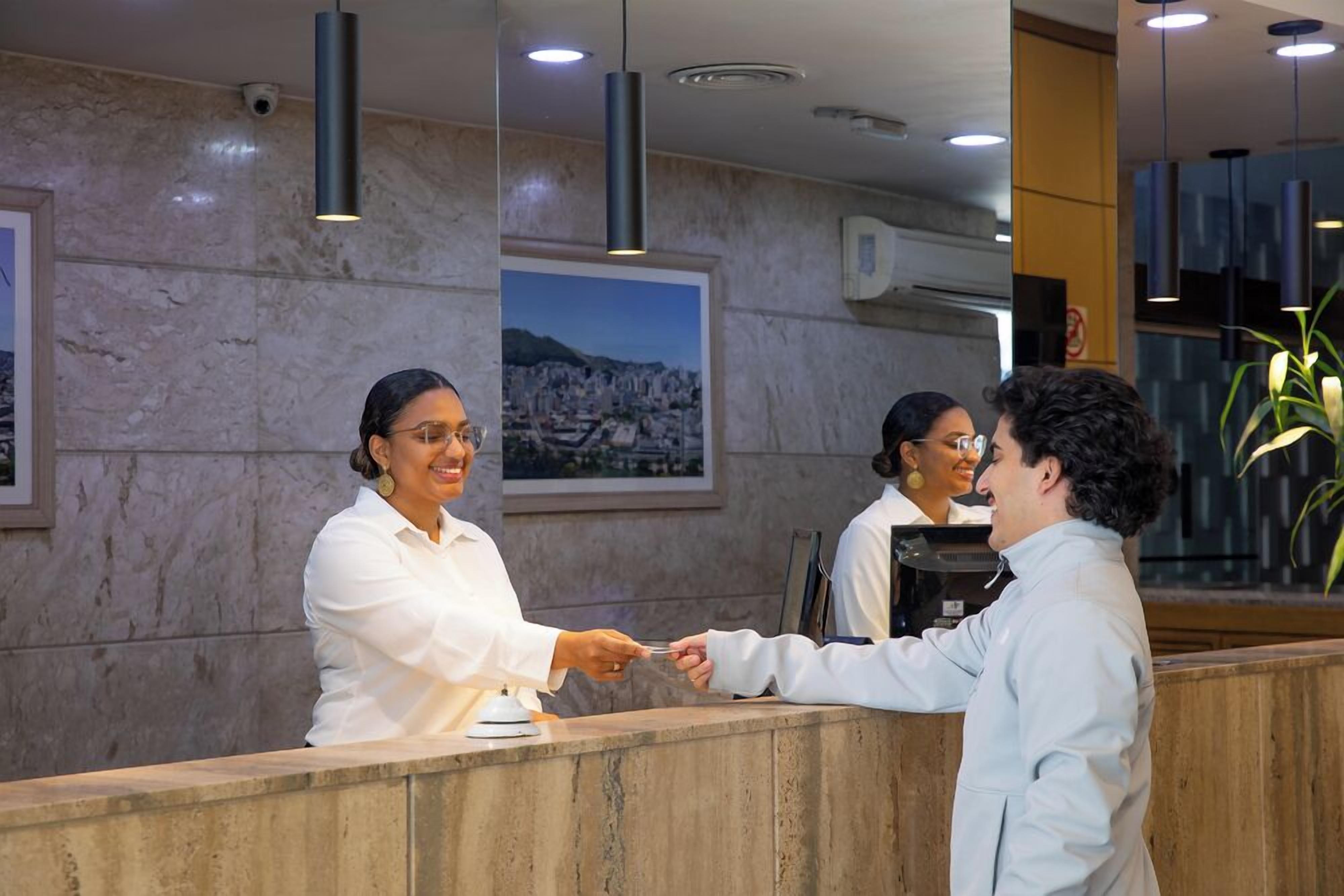 A reception area with marble walls, a framed cityscape picture, and modern pendant lighting.