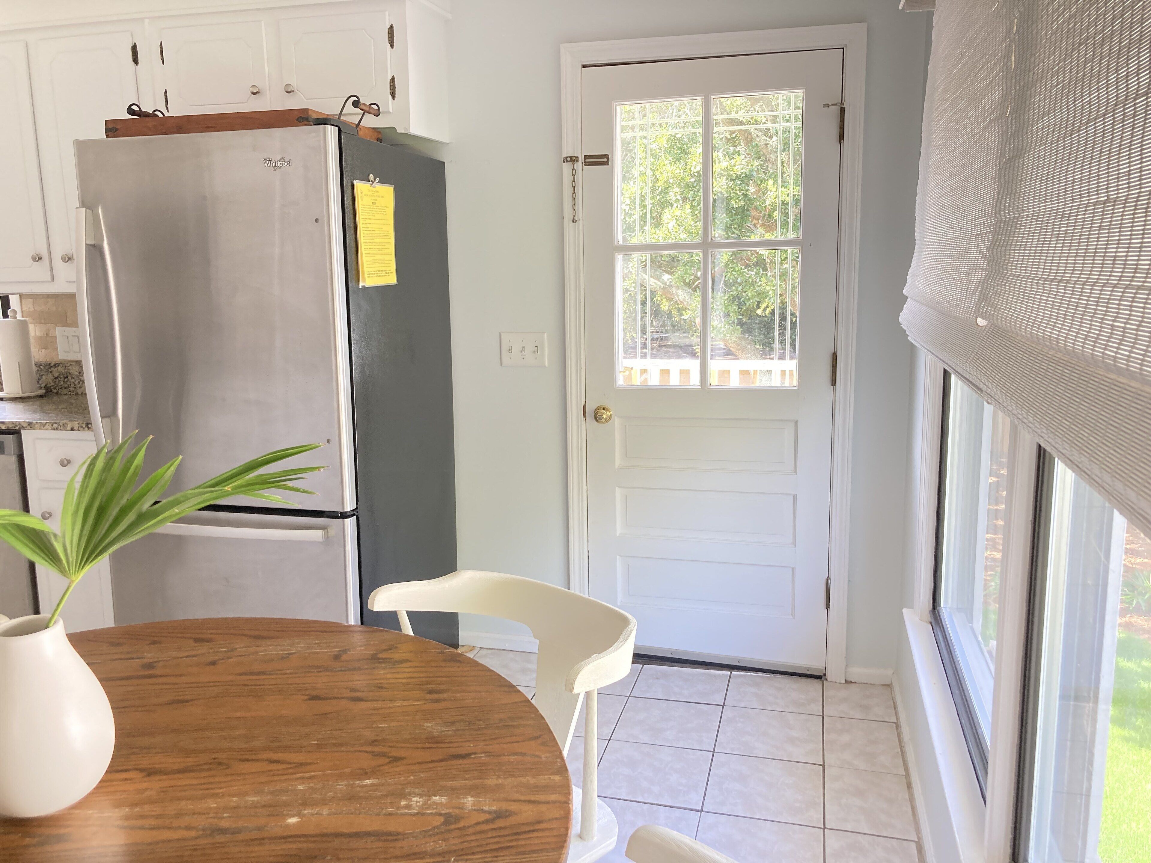 A kitchen with a stainless steel refrigerator, a wooden dining table, and a white chair.