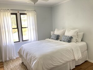 A bedroom with a large bed, white bedding, and two decorative pillows.