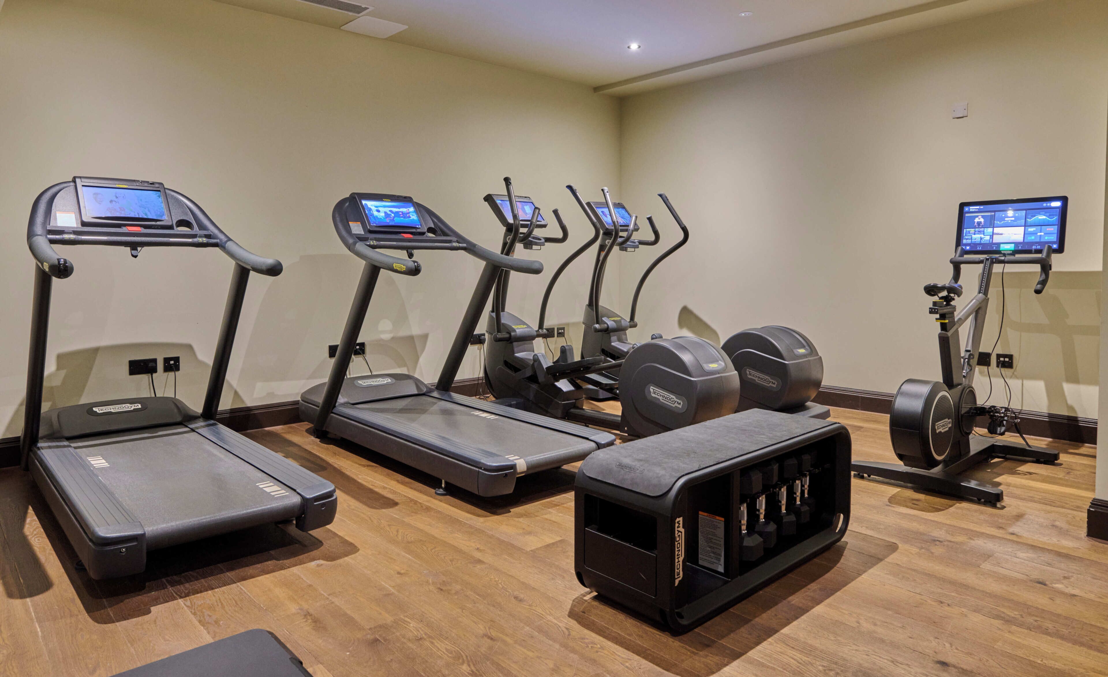 Une salle de sport équipée de tapis de course, de vélos elliptiques et d’un banc de musculation.