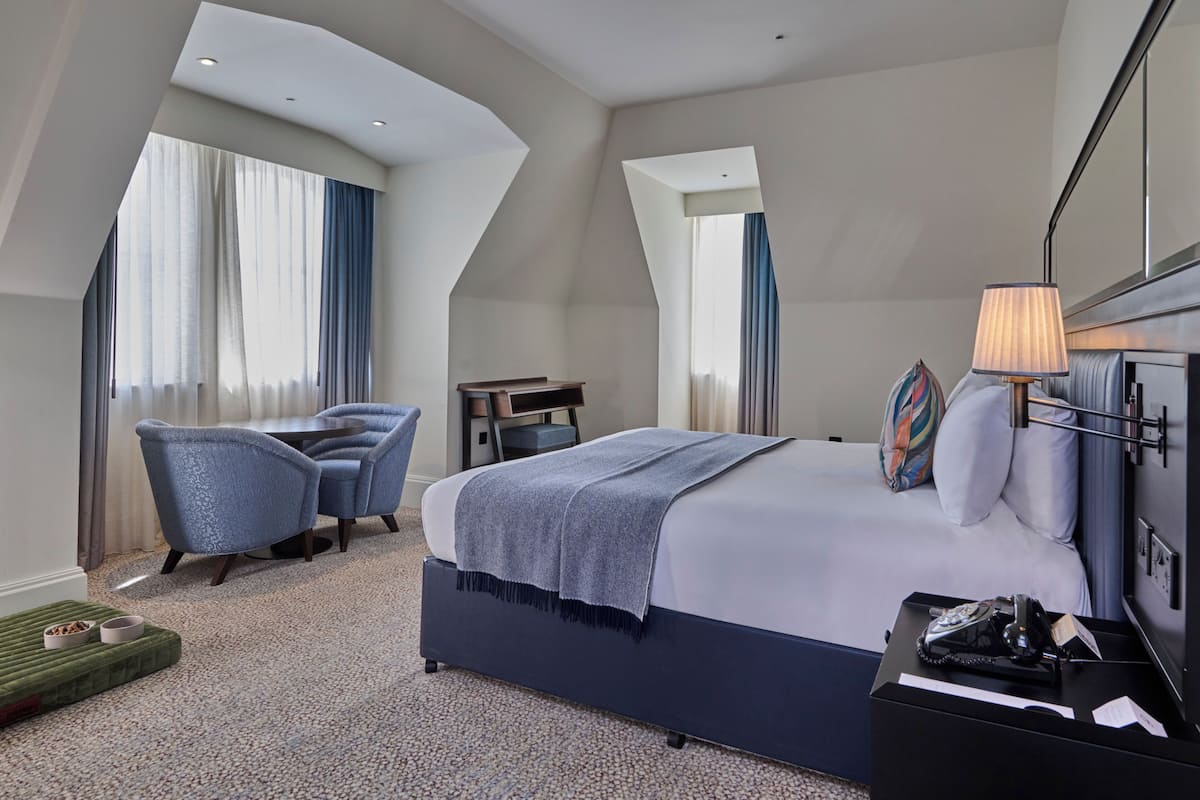 Une chambre d’hôtel moderne avec un grand lit, un bureau, une chaise et une petite table.