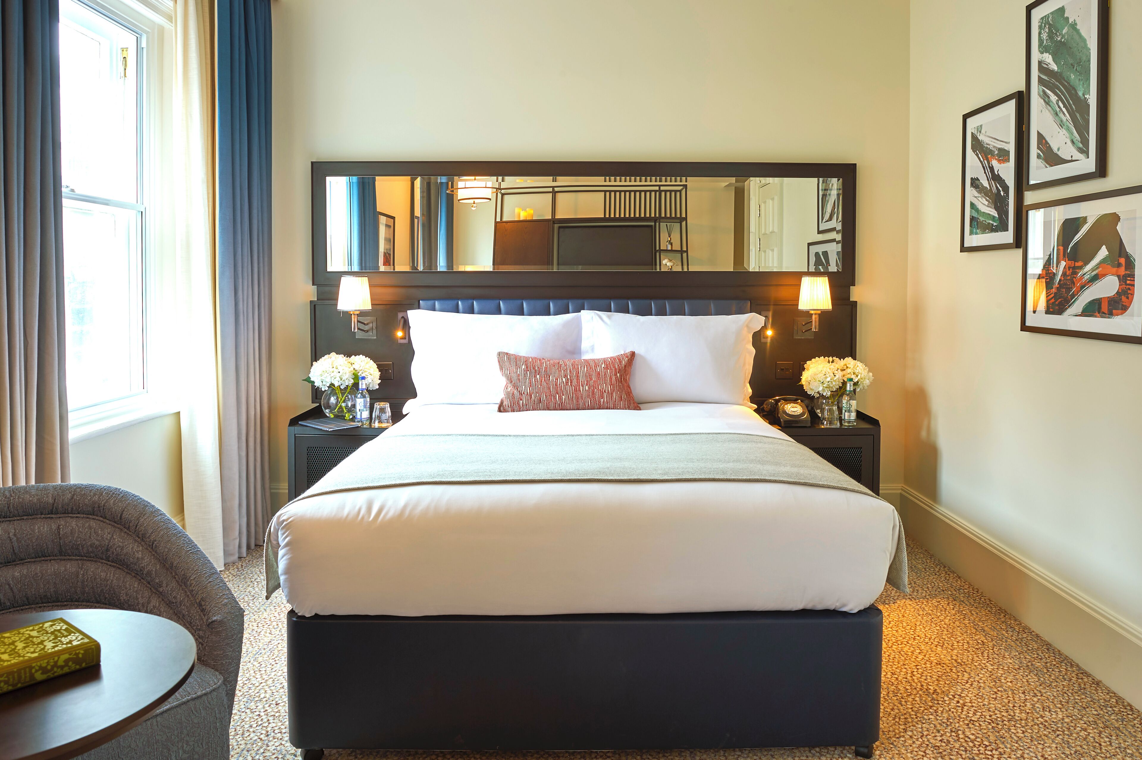 A hotel room with a large bed, two bedside tables, a chair, and a small round table.