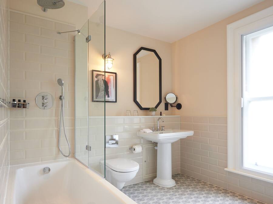A modern bathroom with a glass-enclosed shower, a pedestal sink, and a toilet.